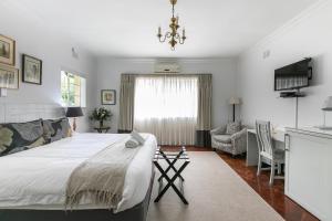 a bedroom with a large bed and a living room at Emmarentia Guest House in Johannesburg