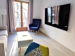 ein Wohnzimmer mit Fernseher und einem blauen Sessel in der Unterkunft Apartamentos Js Sol Rastro in Úbeda