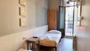 mały pokój z 2 łóżkami i stołem w obiekcie Paraiso Hostel w Barcelonie