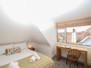 a bedroom with a bed and a desk and a window at Nine Barrow View in Swanage