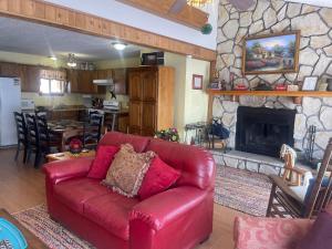 - un canapé en cuir rouge dans un salon avec une cheminée en pierre dans l'établissement Yellow Rose, à Tucumcari