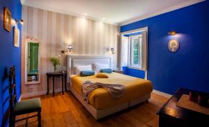 een blauwe slaapkamer met een bed en een blauwe muur bij Palácio de Sintra Boutique House in Sintra