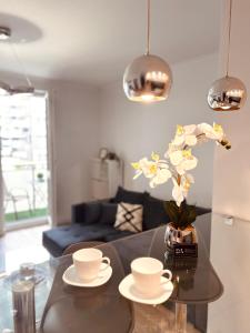 a table with two cups and a vase with flowers at Downtown Apartments Presley air-conditioned in Rzeszów