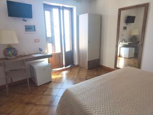 1 dormitorio con cama, escritorio y espejo en B&B Oliva en Scala