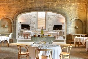 a restaurant with white tables and chairs and a stone wall at Pousada Mosteiro de Amares in Bouro