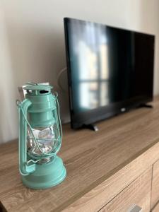 a green glass jar sitting on a table in front of a tv at Al-Dom Apartamenty Dworcowa 9 in Kołobrzeg