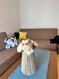 a vase with flowers on a table in a living room at Al-Dom Apartamenty Dworcowa 9 in Kołobrzeg