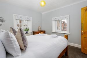 a bedroom with a white bed with pillows and two windows at Air Host and Stay - Anfield cottage, 2 bedroom 2 bathroom in Liverpool