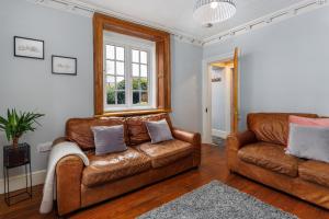een woonkamer met 2 leren banken en een raam bij Air Host and Stay - Anfield cottage, 2 bedroom 2 bathroom in Liverpool