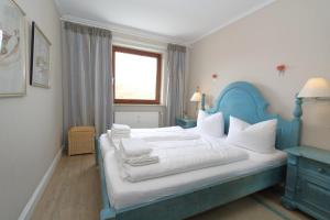 ein Schlafzimmer mit einem blau-weißen Bett und einem Fenster in der Unterkunft Riebschläger - Strandübergang K.Christiansen in Westerland