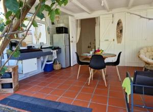 een keuken met een tafel en stoelen op een tegelvloer bij Le Biabiany in Bouillante