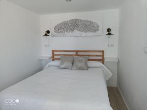 a bedroom with a white bed with two pillows at VuT Dalia in Ávila