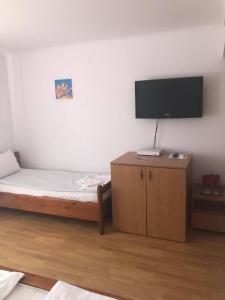 a bedroom with a bed and a flat screen tv at Pensiunea Oșencuța in Talmesch