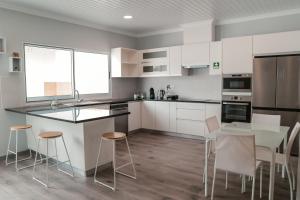 cocina con armarios blancos, mesa y sillas en Casa Maresia en Fenais da Luz