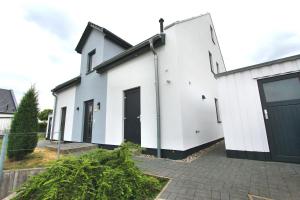 uma casa branca com portas pretas e um pátio em VILLA HUeGEL _ OG_Fewo em Göhren-Lebbin
