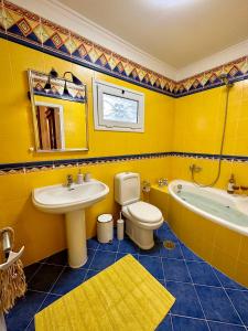 a yellow bathroom with a sink and a toilet and a tub at Aegean Blue House - Spectacular Seaview in Kalámion