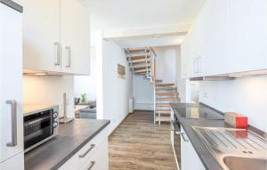 a kitchen with white cabinets and a staircase at Seewolke 12 in Süssau