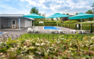 De Heen的住宿－Awesome Home In De Heen With Wifi，后院设有游泳池和2把蓝色遮阳伞