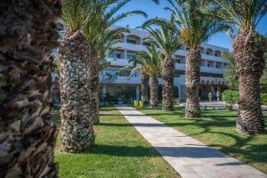 een rij palmbomen voor een gebouw bij IALYSSOS BAY HOTEL in Ialyssos