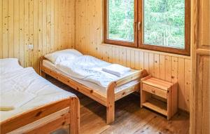 two beds in a wooden room with a window at Cozy Home In Debki With Kitchen in Dębki