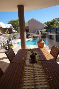 a wooden table and chairs on a patio with a pool at Gecko Lodge Kalbarri in Kalbarri