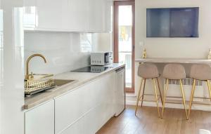 a kitchen with white cabinets and a sink and two stools at Stunning Apartment In Stegna With Wifi in Stegna