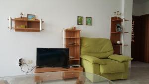 a living room with a green chair and a television at Monastery Apartment 14, St. Vlas in Sveti Vlas