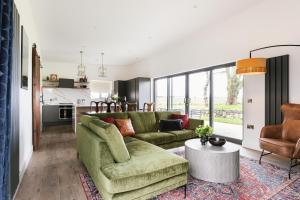 a living room with a green couch and a table at The Barn at Corrstown Village in Portrush