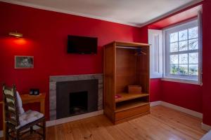 a living room with a fireplace and a red wall at Casa do Vinho Sintra Guest House in Sintra