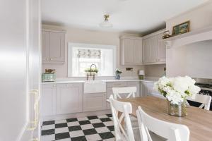 una cucina con armadi bianchi e un tavolo con fiori bianchi di The Farmhouse at Corrstown Village a Portrush