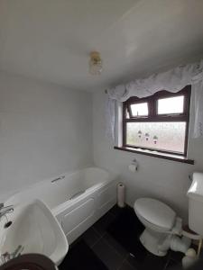 baño con bañera, aseo y ventana en 4 Bedroom Traditional Irish Farm House Killybegs, en Donegal