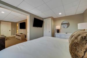 a large bedroom with a white bed and a mirror at 691 Disciples Village Condo in Boyne Falls