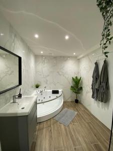 Baño blanco con bañera y lavamanos en Capsule Groovy-Jacuzzi-Sauna-Billard-Netflix- Nintendo Switch & Jeux, en Mons