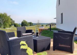 een patio met rieten stoelen en een tafel met een fles wijn bij VILLA ALBA _ OG_Fewo in Göhren-Lebbin