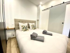 1 dormitorio con 1 cama blanca grande y toallas. en Le Florian By SCLS Locations, en Cannes