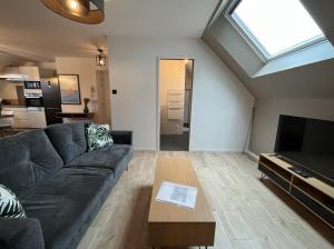 a living room with a couch and a television at Les Pierres de Symphorien - parking gratuit in Vannes