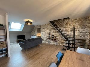 a living room with a couch and a brick wall at Les Pierres de Symphorien - parking gratuit in Vannes