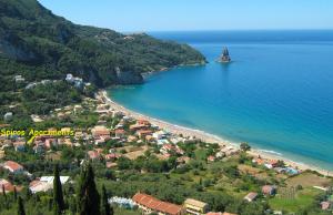 Blick auf einen Strand mit einem Resort und das Meer in der Unterkunft Spiros Apartments - Agios Gordios Beach, Corfu, Greece in Agios Gordios