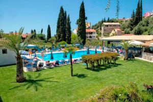 a resort with a swimming pool and people sitting around it at Spiros Apartments - Agios Gordios Beach, Corfu, Greece in Agios Gordios