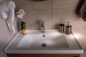 een wastafel in een badkamer met een telefoon en een bloem bij Villas Thalia in Zakynthos +53 foto's