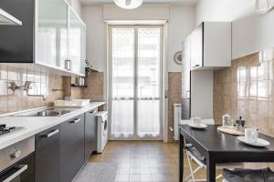 フィレンツェにあるFlorence Modern & Bright Apartment!の白いキャビネットと黒いテーブル付きのキッチン
