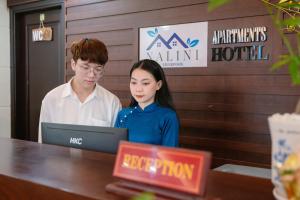 a man and a woman sitting at a table with a laptop at NALINI Hotel & Apartment in Da Nang