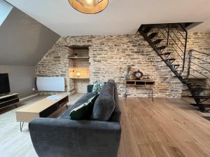 a living room with a couch and a stone wall at Les Pierres de Symphorien - parking gratuit in Vannes