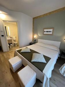 a bedroom with a large bed with two white stools at Hotel Regina in Grado