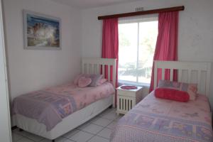 a bedroom with two beds and a window with red curtains at Laguna La Crete 47 in Margate