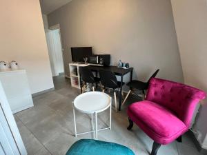 ein Wohnzimmer mit einem rosa Stuhl und einem Tisch in der Unterkunft Key-s Meaux/Suite8Luna/centre/Disney in Meaux