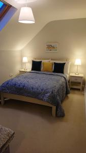 a bedroom with a bed with a blue comforter and two lamps at Melroche House Doolin in Doolin