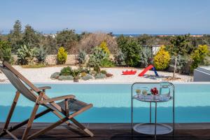 a chair and a glass table next to a swimming pool at Alba Bianca Villa, a Secluded Retreat, By ThinkVilla in Hersonissos