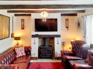 a living room with leather couches and a fireplace at Borough Beck Cottage in Helmsley