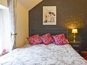 a bedroom with a bed with red and white pillows at Borough Beck Cottage in Helmsley